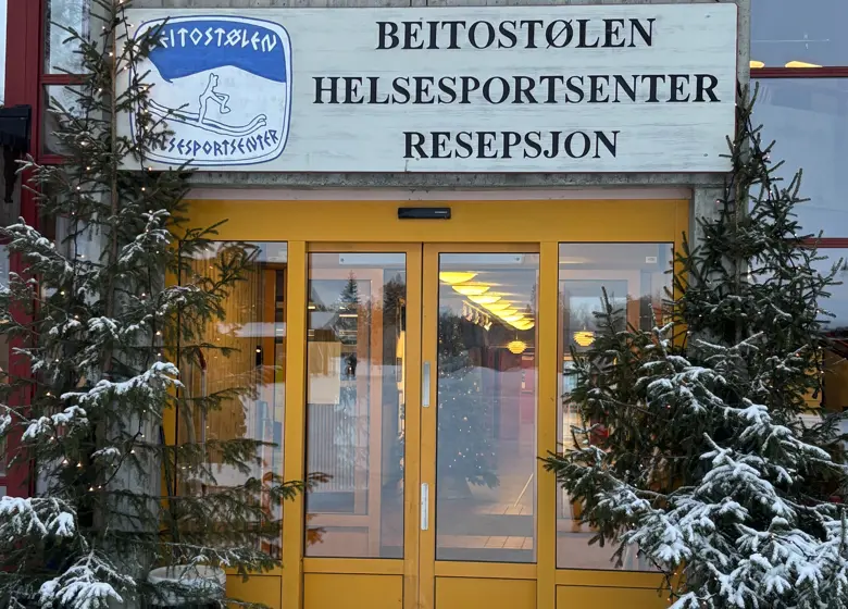 Juletrær omkranser hovedinngangen til Beitostølen Helsesportsenter