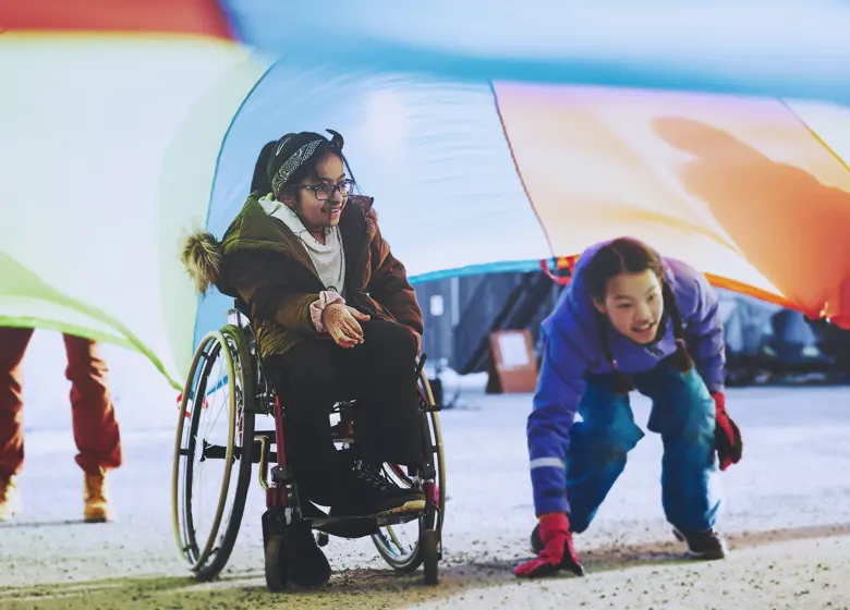 To jenter under en fargerik fallskjerm. Foto: Christine Stokkebryn