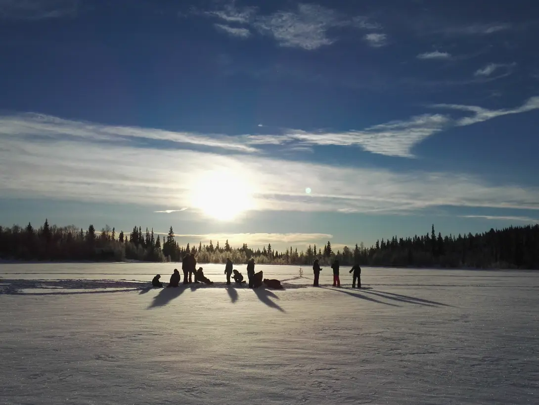 Voksne og barn pilker på Bamselitjern i lav vintersol