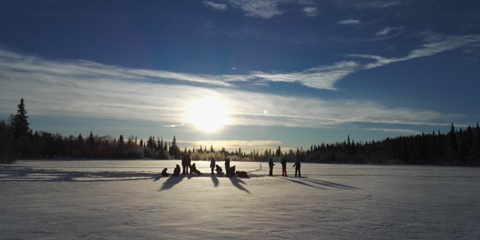 Voksne og barn pilker på Bamselitjern i lav vintersol